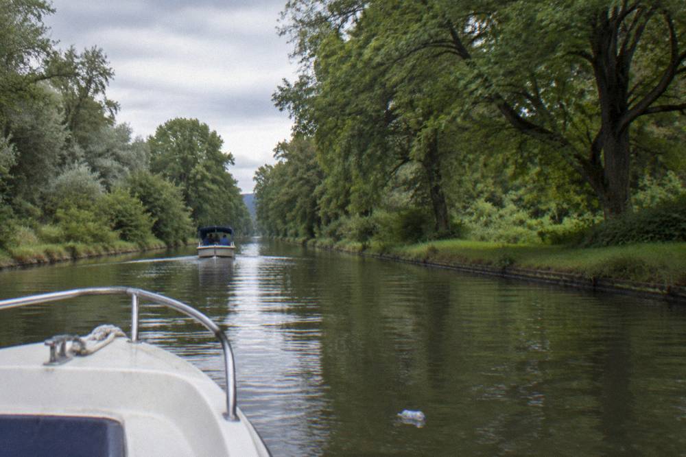 A canal boat cruising a straight tree-lined reach of the Erie Canal