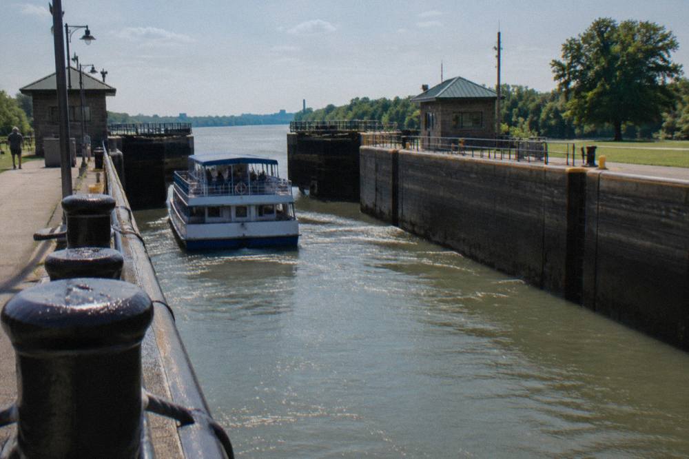 A tour boat descending inside a lock chamber as gates stand open ahead