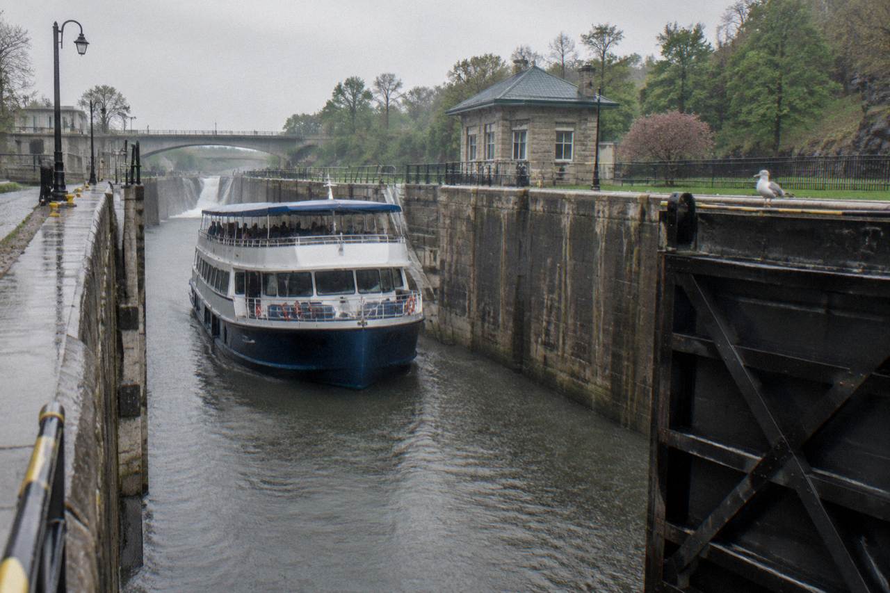 A canal boat sitting in a chamber between tall stone and concrete lock walls as water fills the chamber