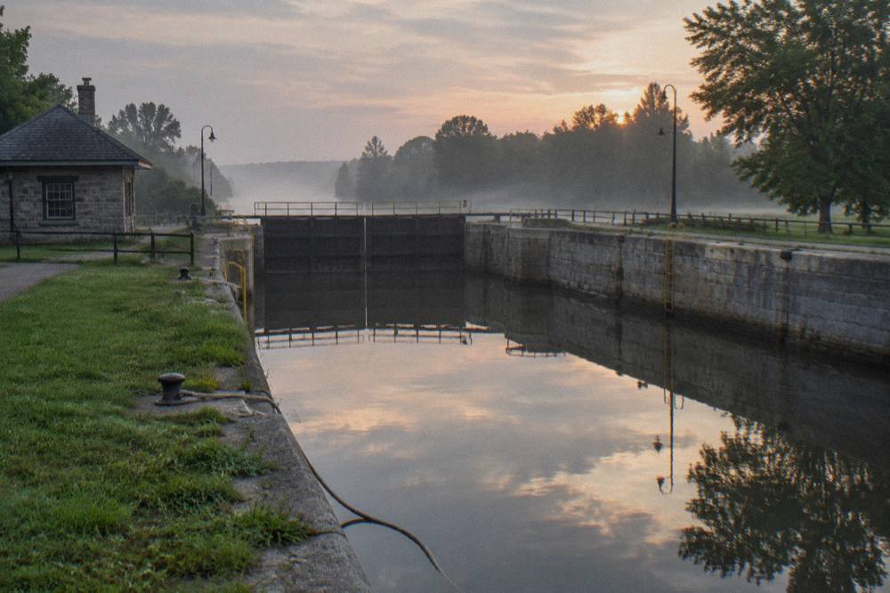 A canal lock chamber with closed gates and still water reflecting the sky