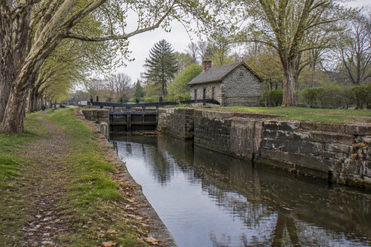 A calm stretch of the Erie Canal with stone lock walls and a tree lined bank