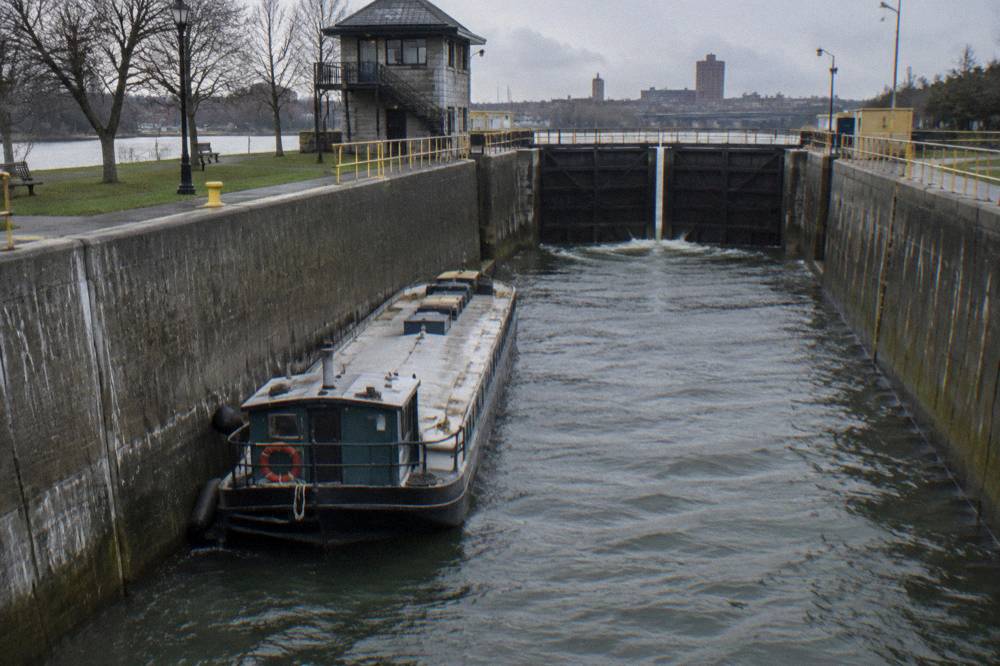 A canal boat passing through a large lock chamber with gates closing behind it