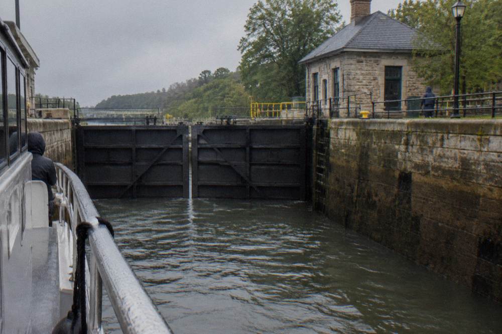 A lock gate on the Erie Canal closing as a boat waits inside the stone chamber