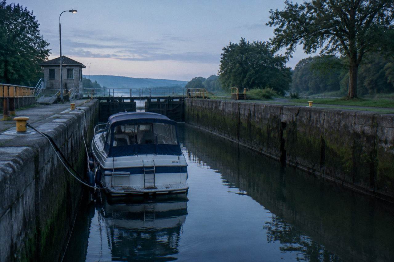 A canal boat moving through a lock chamber on the Erie Canal with stone lock walls and calm water