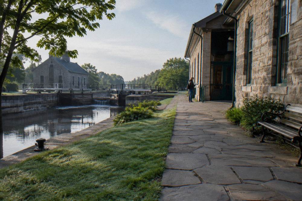 Canal-side walkway and stone architecture of the Lockport locks district under a clear sky