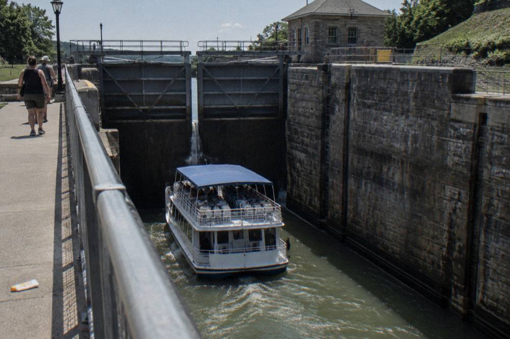 A tour boat rising inside a tall stone lock chamber with lift gates closing
