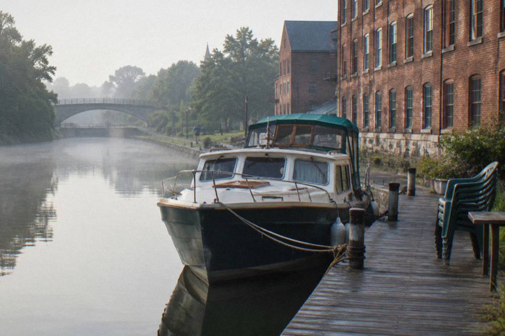 A canal boat tied up at a village dock beside a converted mill building