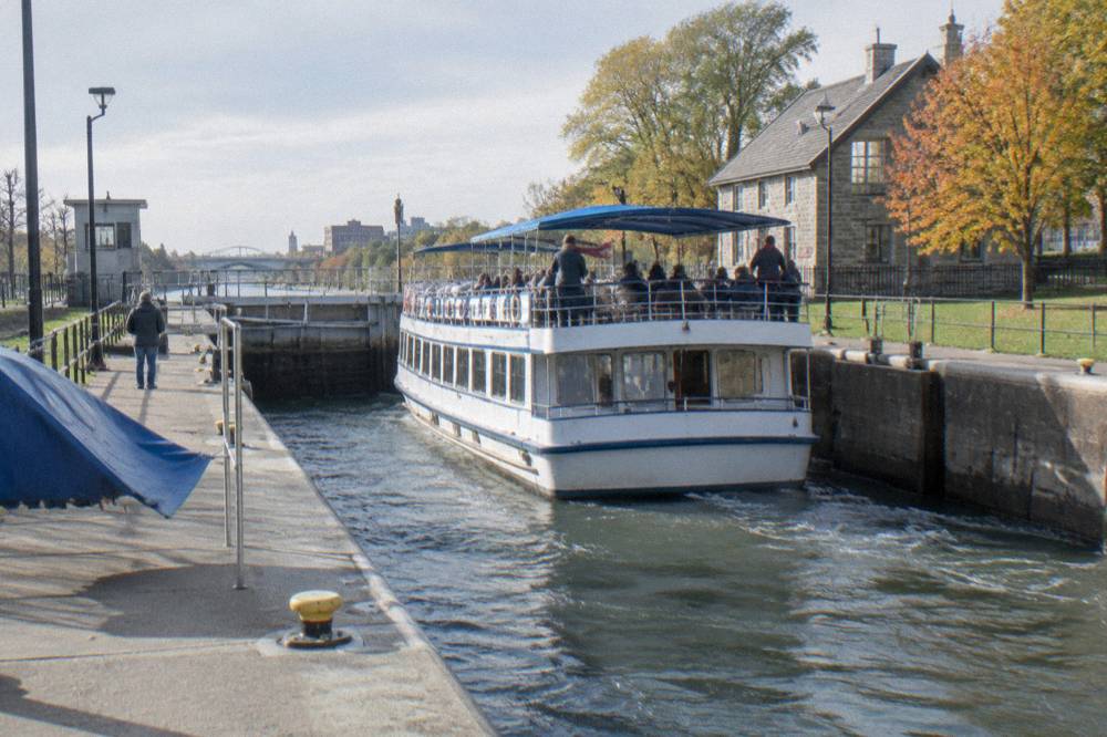 Cruise boat passing through a filled Erie Canal lock in autumn