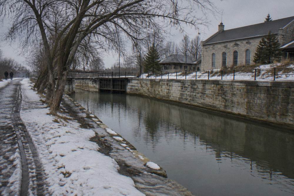 Lowered Erie Canal channel beside a stone embankment in winter