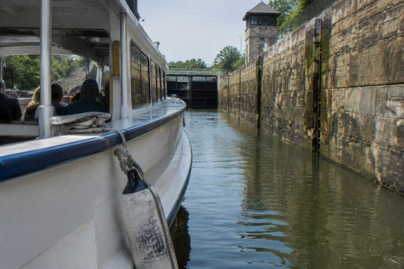 A lock cruise boat in Lockport with the canal walls rising behind it