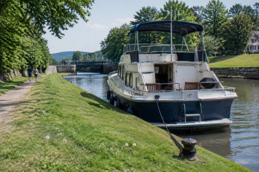 A canal boat tied up along a grassy towpath on the Erie Canal