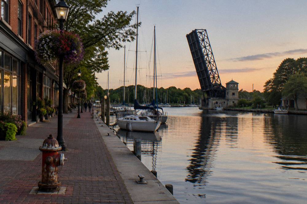 A village main street beside a canal basin with a lift bridge in the background