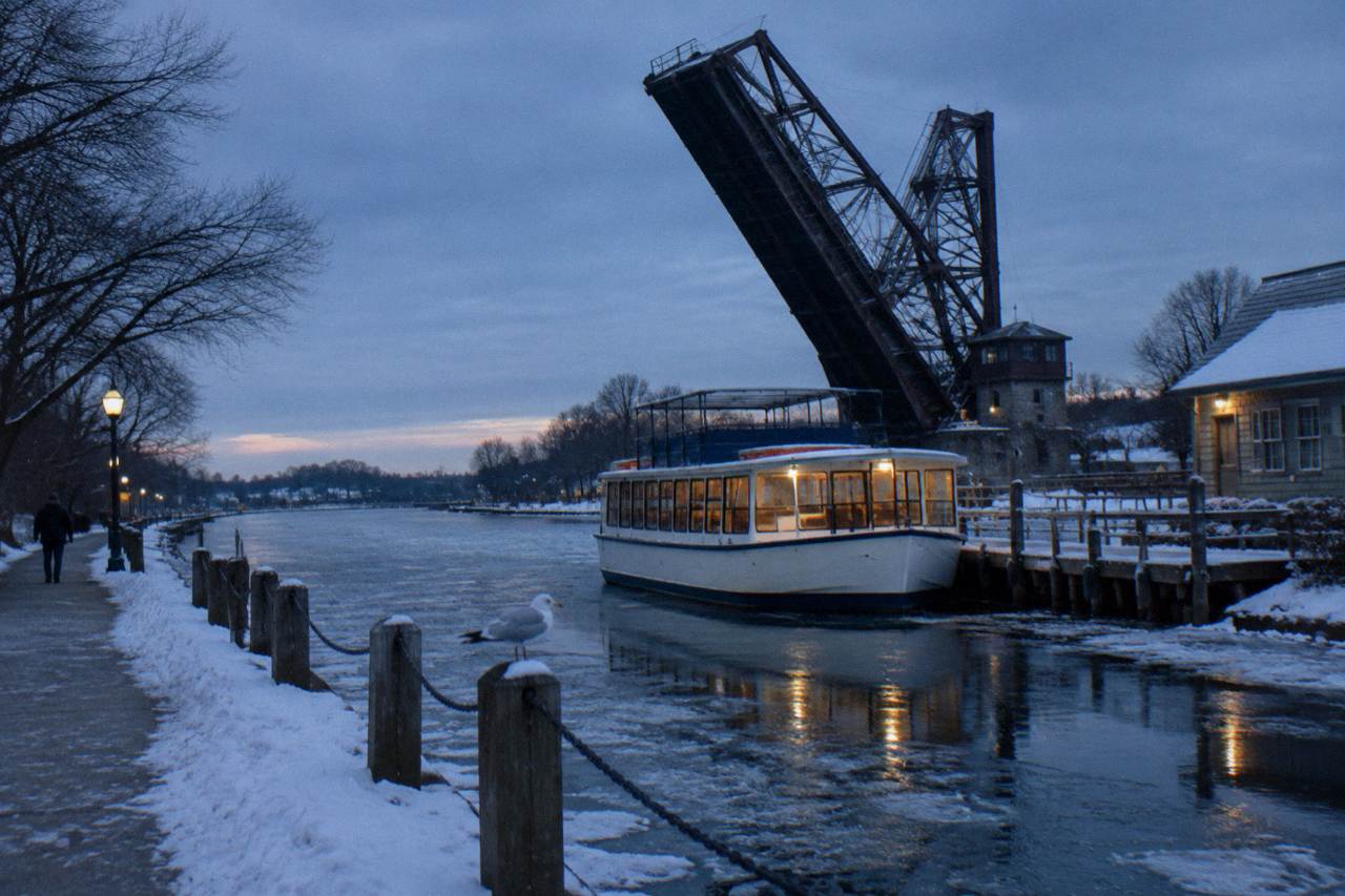 A canal boat tied up at a village dock beside a lift bridge on the Erie Canal