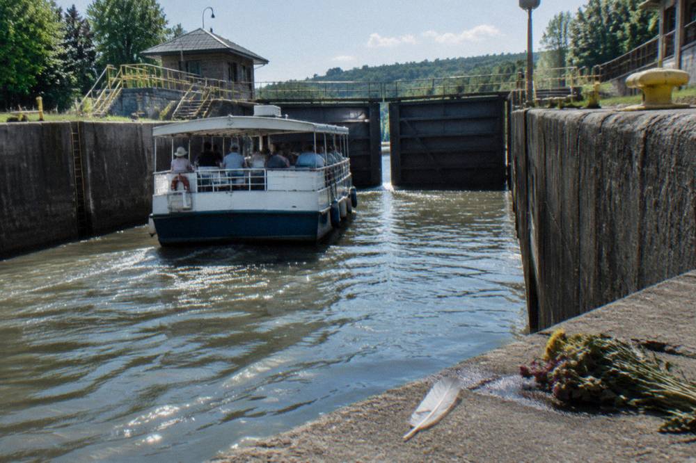 A canal tour boat entering a lock chamber with gates closing behind it