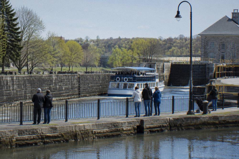 A canal dock with a tour boat at the gate and visitors gathered along the railing