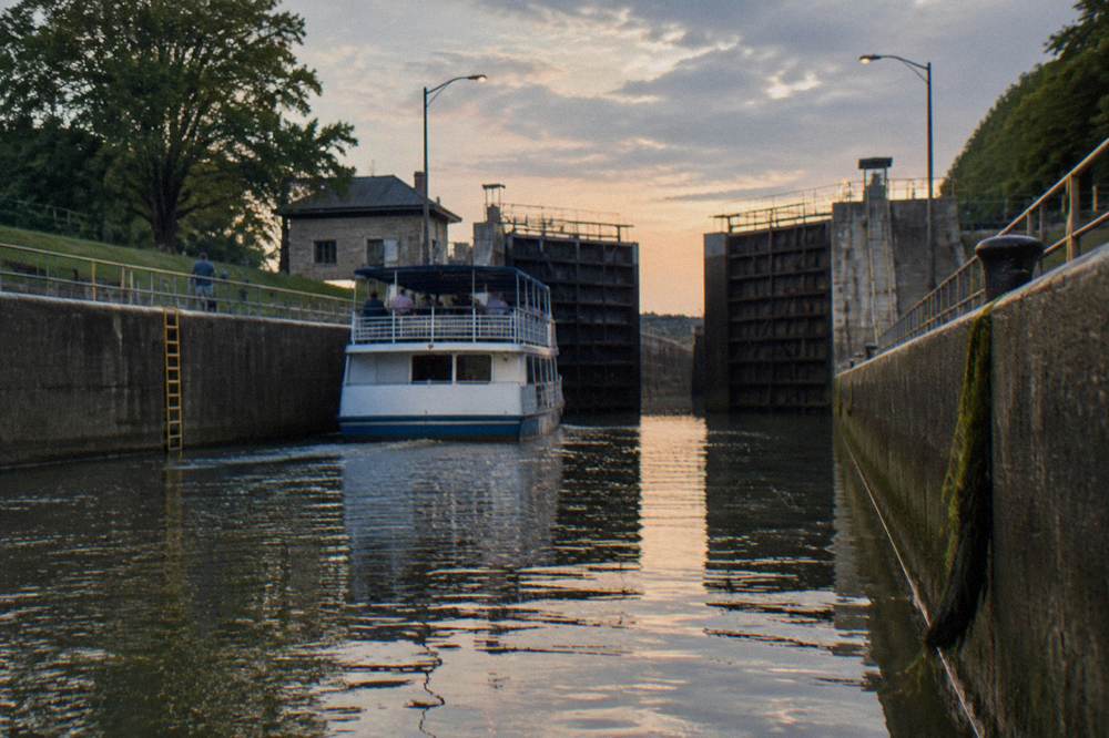 A modern cruise boat entering a large concrete lock chamber on the Erie Canal