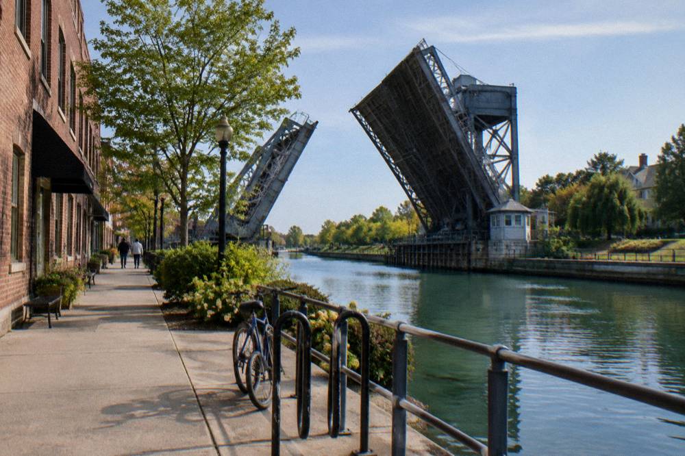 A village main street where shops and restaurants face the Erie Canal and a lift bridge