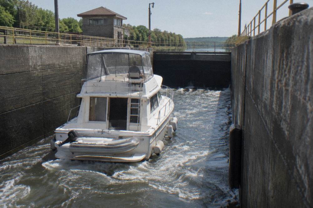 A small passenger boat passing through a canal lock as water fills the chamber