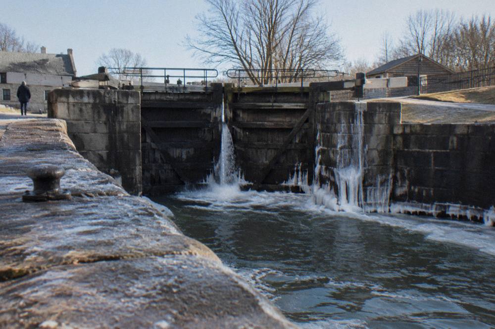 Massive wooden lock gates on the Erie Canal with water flowing through a partially opened sluice