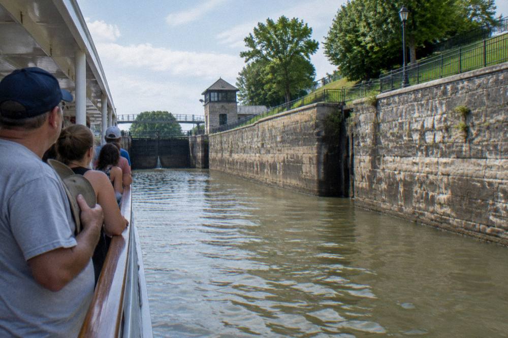 Tour boat passengers seated along the rail inside a lock chamber as gates close ahead