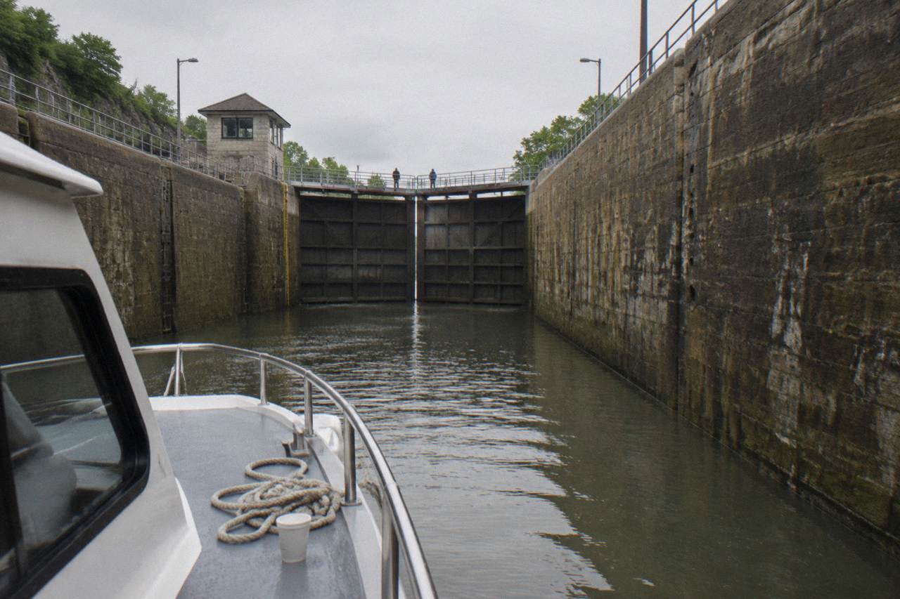 A tour boat resting inside a stone Erie Canal lock chamber with gates closed