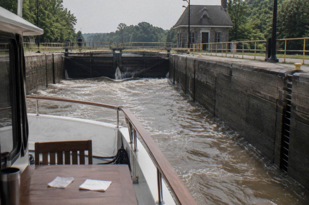A canal boat passing through a lock with water rushing, seen from the deck
