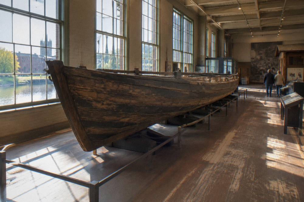 A museum gallery with canal exhibits and a full-size boat hull displayed indoors