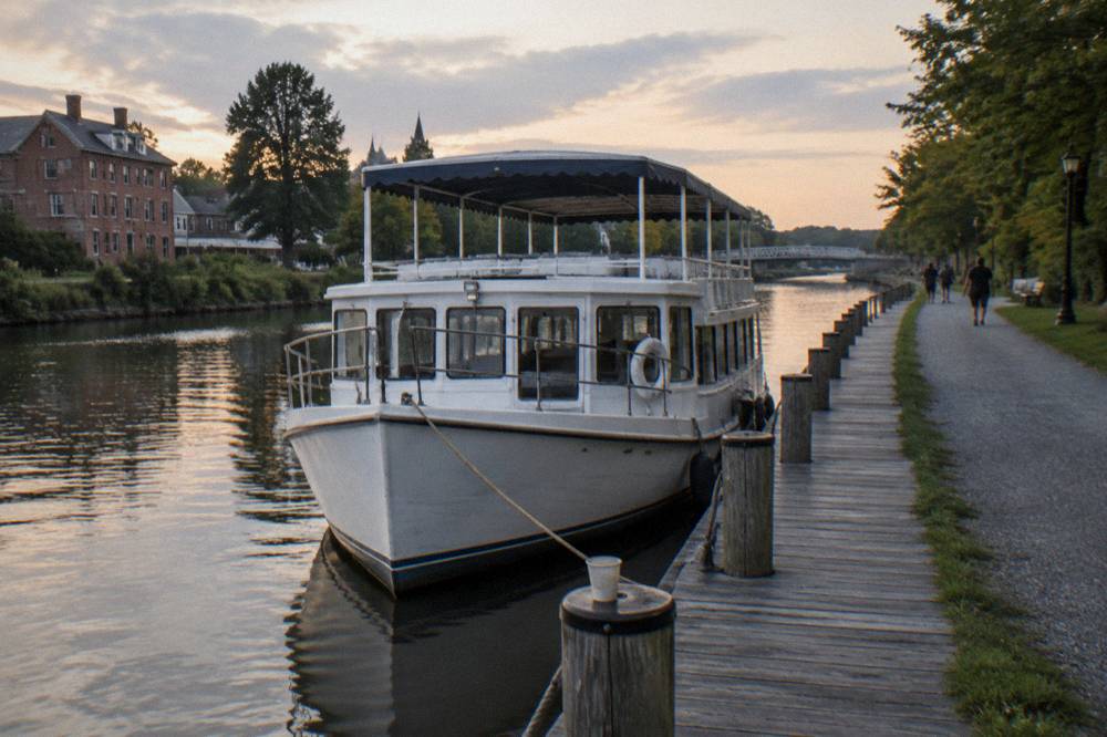 Canal cruise boat tied up at a village dock beside a bike path