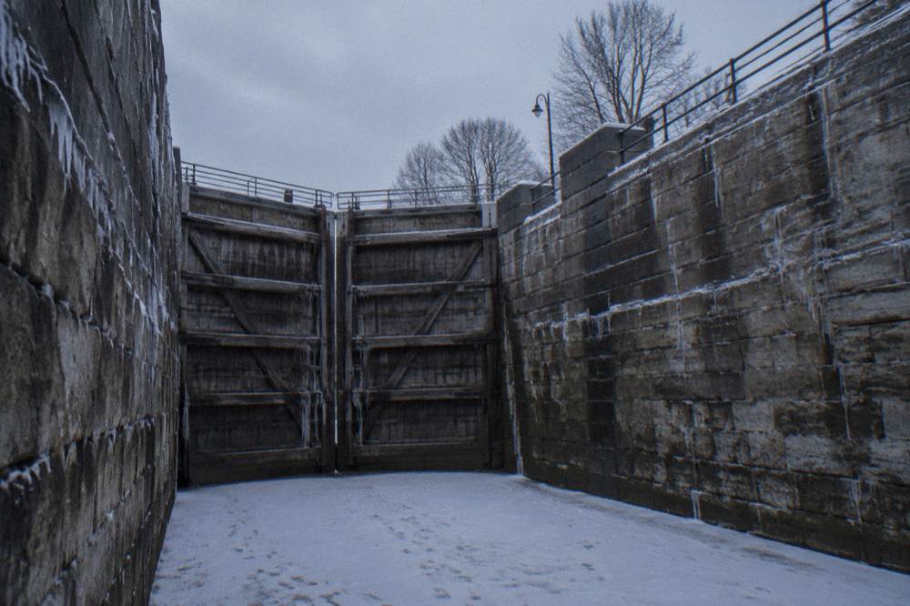 Wooden lock gates of a restored old canal lock with stone walls and empty chamber