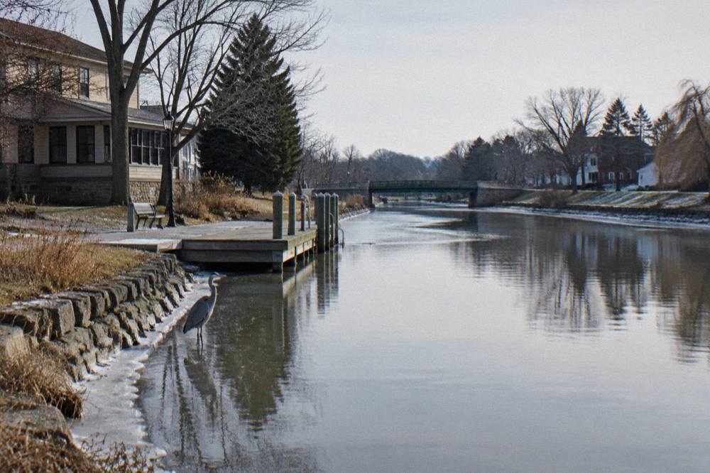 A wide canal channel with a lift bridge in the distance and still water reflecting the sky