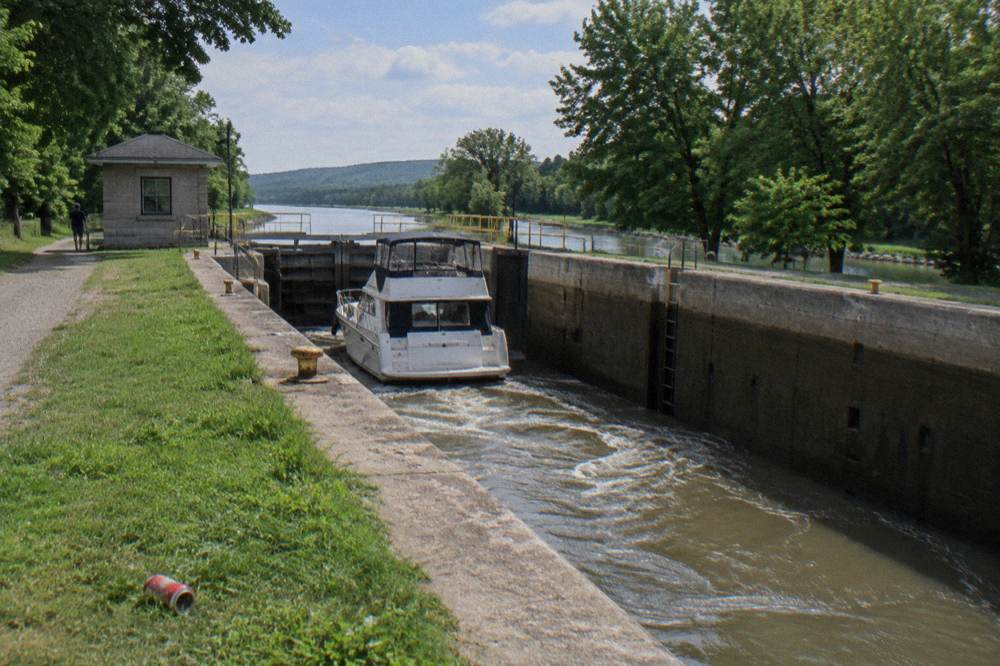 A lock chamber filling with water as gates stand open along a tree-lined canal