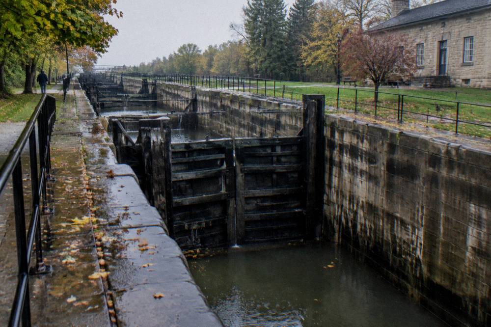 Stone lock walls and wooden gates of restored historic locks beside a modern canal channel
