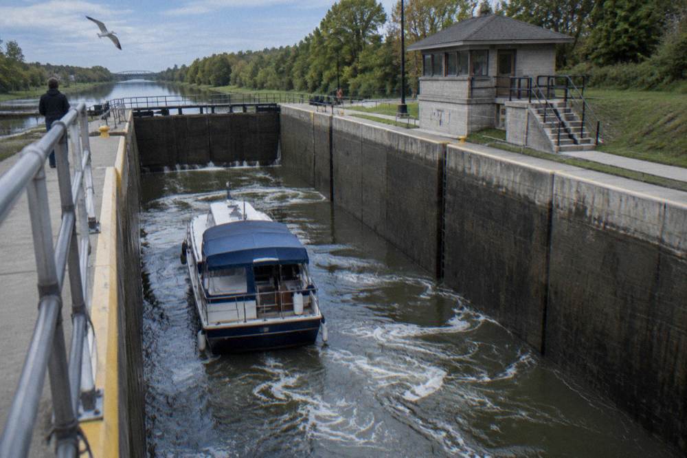 A canal boat inside a lock chamber with water swirling as the level rises between stone and concrete walls.