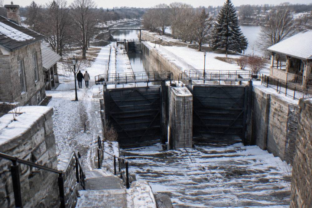 Two modern canal lock gates standing side by side above a restored stone lock staircase