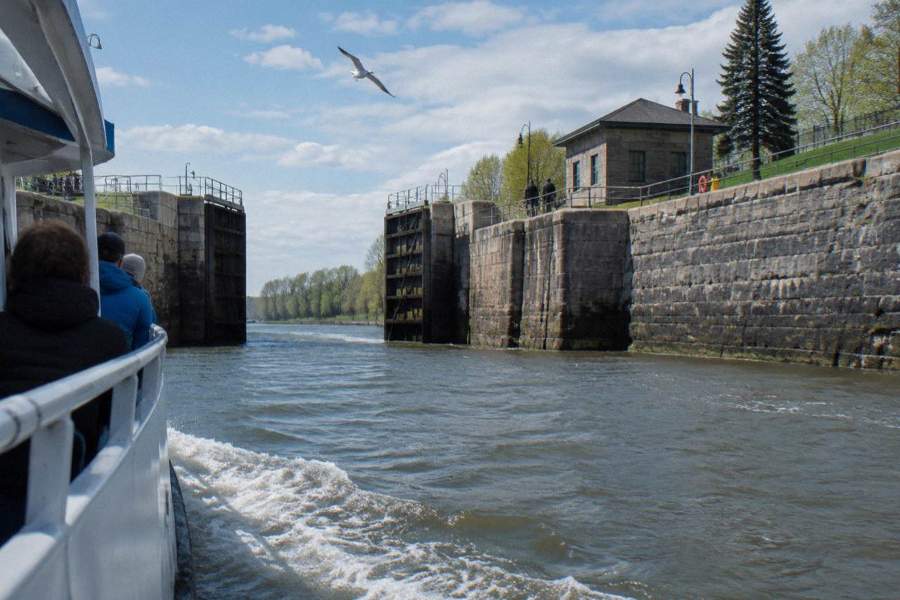 A tour boat entering a set of Erie Canal lock gates with stone walls on both sides